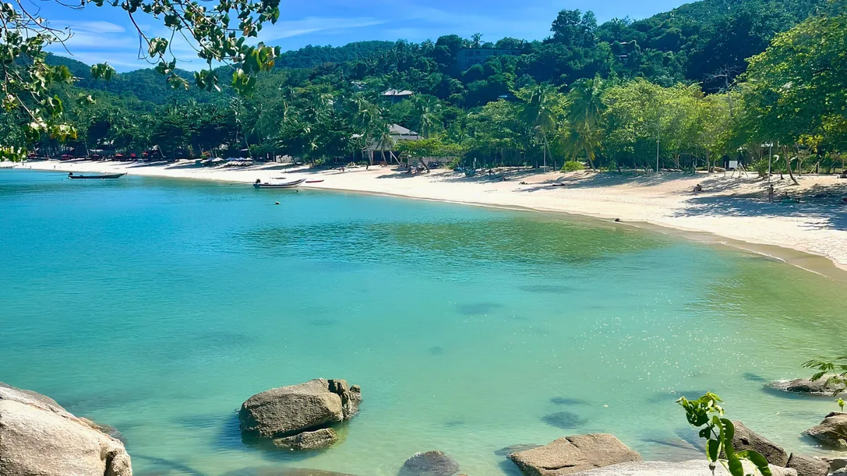 Tropical beach with turquoise water, white sand, and lush green hills